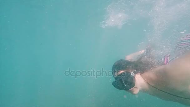 Jonge vrouw in full-face masker duikt in het water. Snorkelen in tropische zee, actieve vakantie. Slow motion. - Video