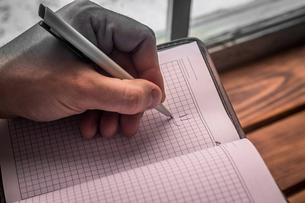 Ανδρικά αριστερό χέρι με στυλό σχέδιο χαμόγελο στο σημειωματάριο - Φωτογραφία, εικόνα
