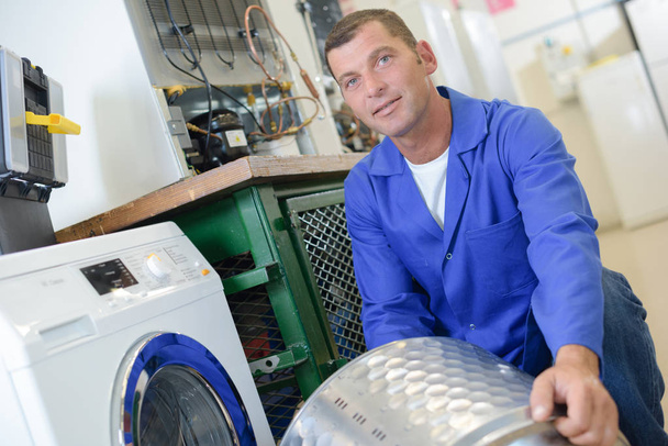 Reparador com tambor de máquina de lavar roupa
 - Foto, Imagem
