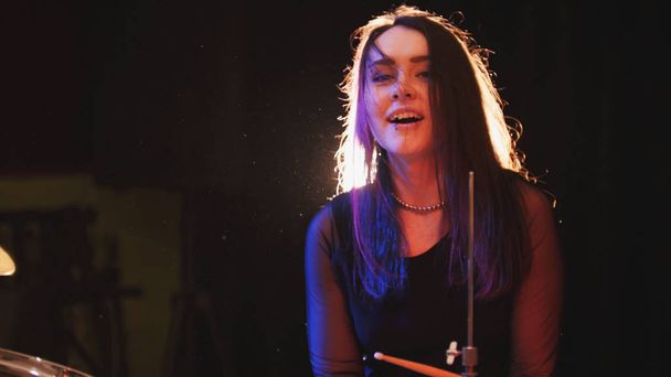 Temperamentní bubeník atraktivní dívka s černými vlasy na garáž - rocková kapela - Fotografie, Obrázek