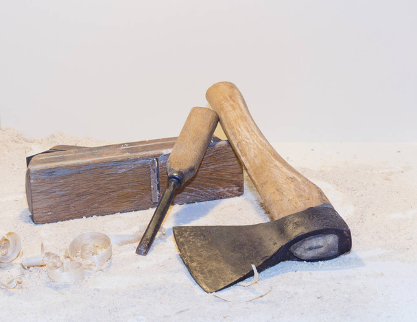 Старый топор, плоскость, зубило и древесные стружки на светлом фоне
 - Фото, изображение