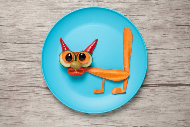 Удивительная кошка, сделанная из моркови и огурца на тарелке и столе
 - Фото, изображение