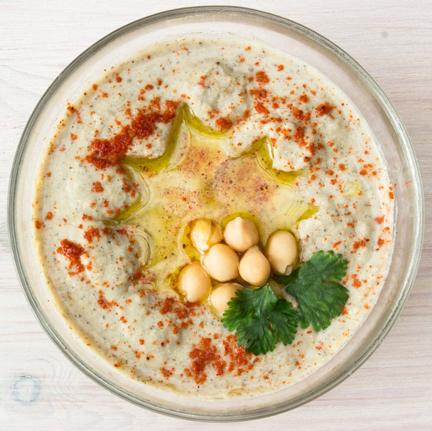 A bowl of creamy hummus with olive oil. - Фото, зображення