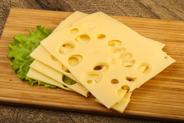 Gesneden kaas met salade bladeren - Foto, afbeelding