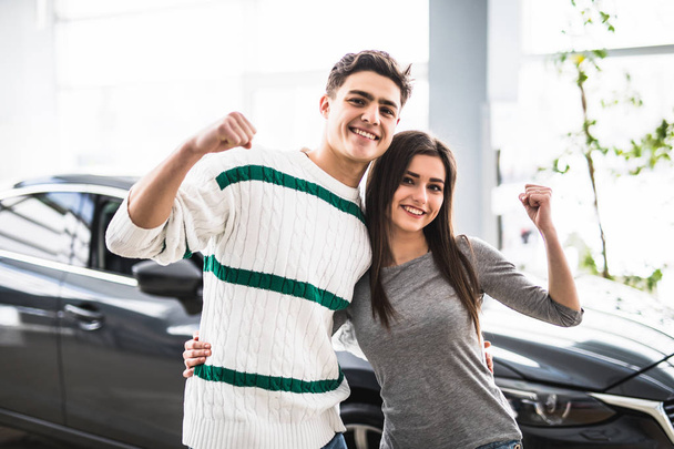 Couple excité acheter une voiture chez le concessionnaire avec les bras en l'air
 - Photo, image