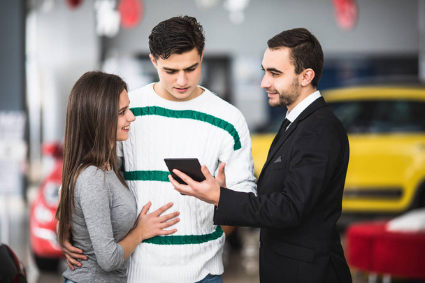 glückliches Paar mit Autohändler Blick auf Tablet in Auto-Show oder Salon - Foto, Bild
