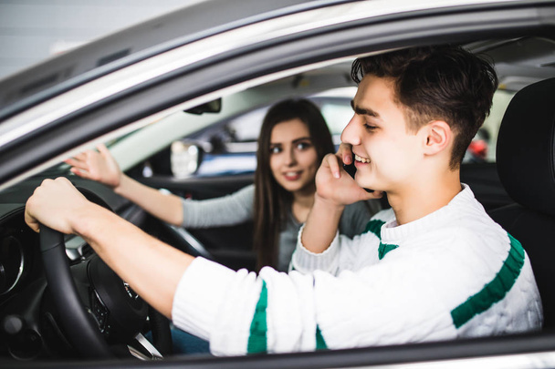 Jeune femme montrant une route devant la voiture pendant que le conducteur utilise un téléphone portable et perd de la concentration. Conduite dangereuse
. - Photo, image