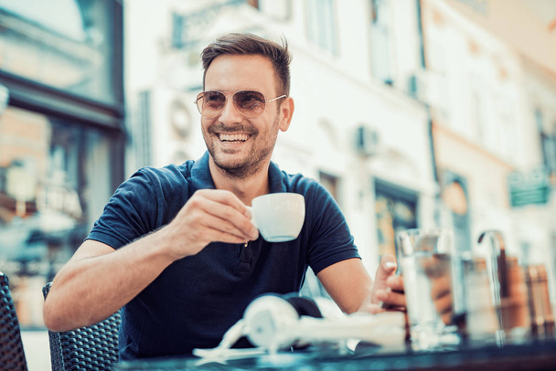 Young man drinks coffee outdoor - 写真・画像
