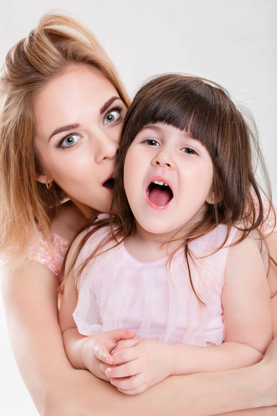 portrait of blonde mom and sweet little daughter in pink dresses - 写真・画像