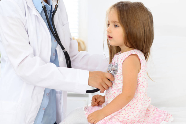 Doctor examining a little girl by stethoscope - Foto, afbeelding