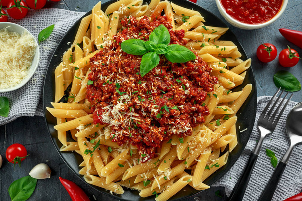Hot Penne pasta boloñesa con queso parmesano, albahaca, ajo, tomates, chile en el plato
. - Foto, Imagen