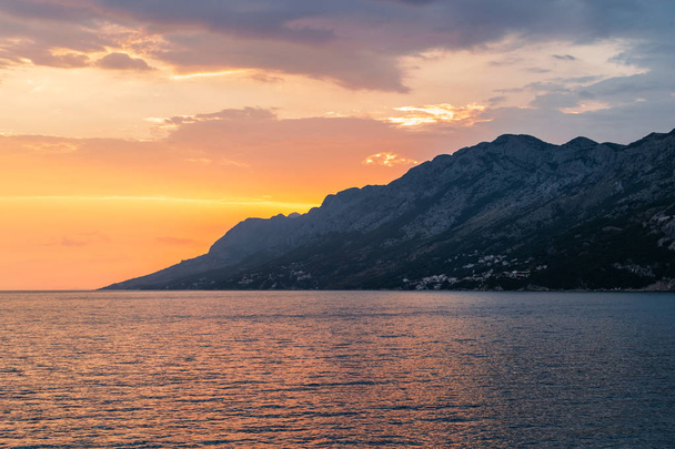 Colorful sunset over the mountain on the Adriatic Sea in Brela, Croatia - Foto, imagen