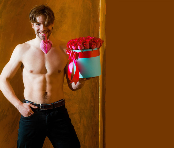 bearded muscular man with sexy body holds red rose box - Zdjęcie, obraz