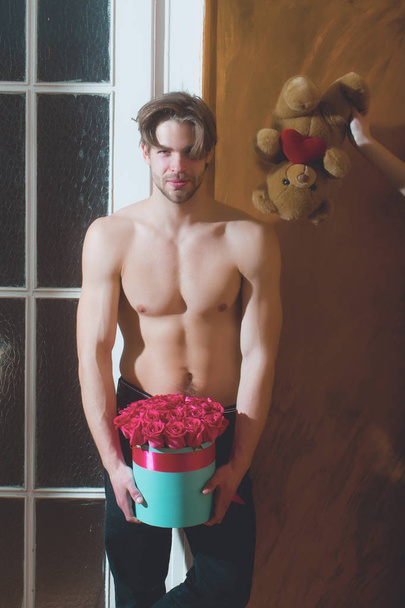 bearded muscular man with sexy body holds red rose box - Foto, afbeelding