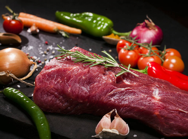 Raw beef steak on a cutting board with rosemary and spices. - Photo, Image