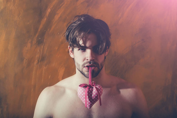 bearded muscular man with sexy body holds pink valentines heart - Zdjęcie, obraz