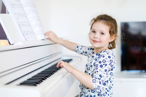 Szép kis gyerek lány nappaliban vagy a Zeneiskolában zongorázni - Fotó, kép