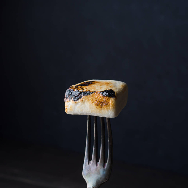 Smoked marshmallow on fork on dark background - Foto, Imagem