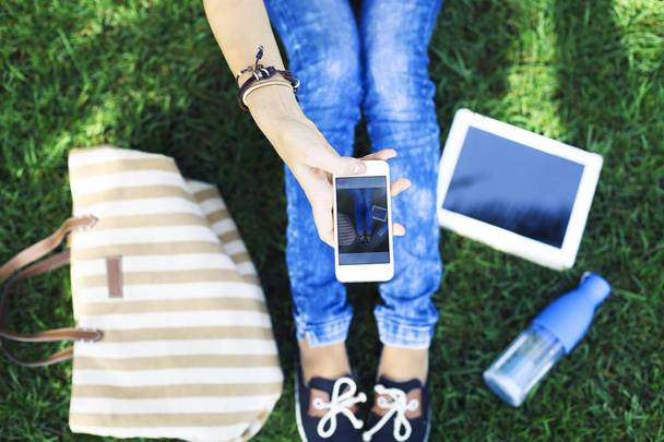 Telefon komórkowy w rękę dziewczyny na zielonej trawie  - Zdjęcie, obraz