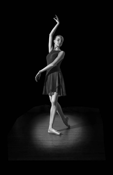 Joven e increíblemente hermosa bailarina posando en la sala de la oscuridad en parquet
. - Foto, Imagen