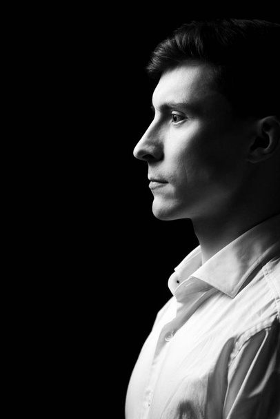 Retrato bajo de un hombre con camisa blanca en blanco y negro
. - Foto, Imagen