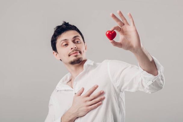 handsome young brunette man in shirt holds in hands red heart on - Foto, Imagem