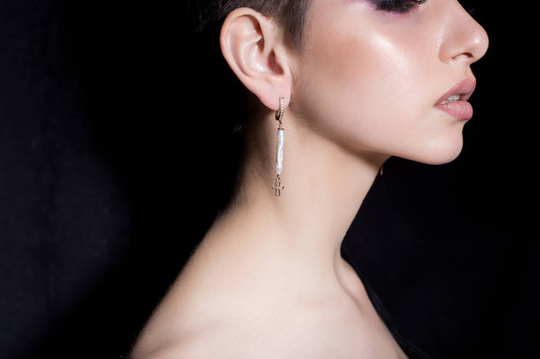 beautiful sexy sensual young girl with short hair with bright makeup in the nude, beautiful evening jewelry earrings, necklaces, bracelets Fashion shot on a black background in the studio - 写真・画像