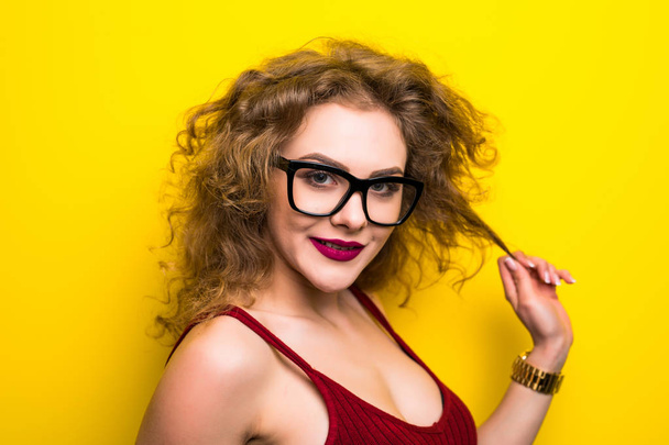Beauty portrait of young girl with curly hairstyle. Girl posing on yellow background, looking at camera, smiling. Studio shot. - Foto, Bild