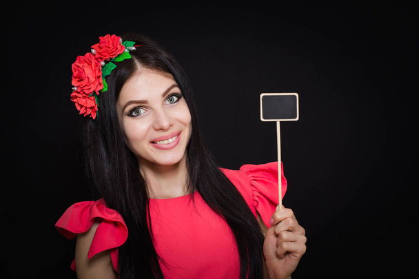 Belle femme avec une couronne de fleurs rouges tient une plaque de bois
 - Photo, image