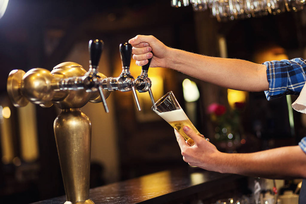 Barman leje świeże piwo w pubie, ręka barman piwo stuknięciu nalewać piwo lager, piwo z kranu, wypełnienie ze szkła z piwa, świeże piwo, pub. Bar.Restaurant.European bar. Amerykański bar. - Zdjęcie, obraz