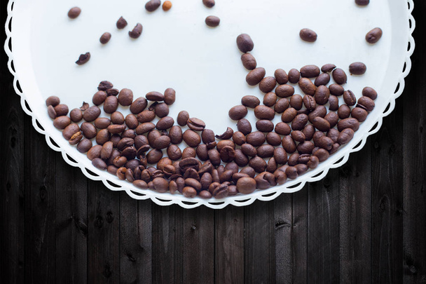 Coffee beans on a white plastic plate. On beautifull wooden background. Love. Insparation. On white plate. - Photo, Image