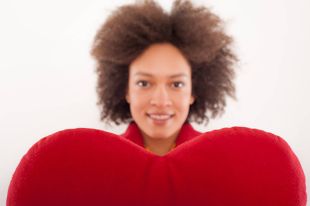 Happy beautiful girl with heart shaped red pillow - Foto, afbeelding
