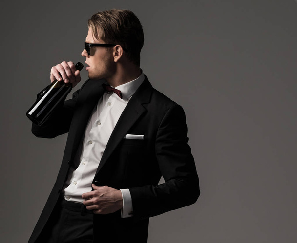 Uomo vestito affilato in abito nero con bottiglia di vino
 - Foto, immagini