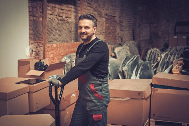 Storekeeper working with pallet truck in a warehouse - Zdjęcie, obraz