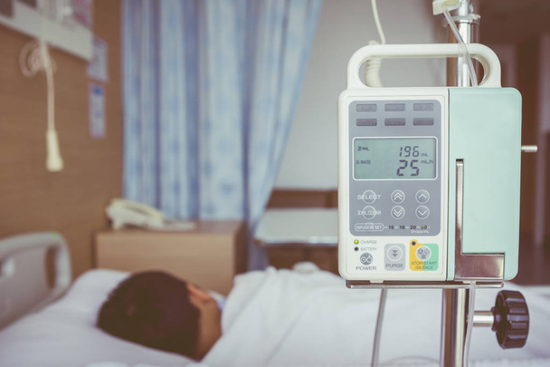 Azjatycki chłopiec leży na łóżko chorego z pompy infuzji dożylnej Iv dri - Zdjęcie, obraz