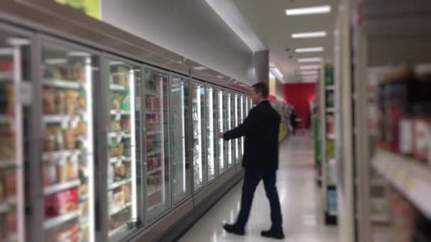 Hombre en las tiendas de comestibles en la sección de alimentos congelados
 - Metraje, vídeo