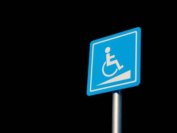 Disabled parking space and wheelchair way sign and symbols on a pole warning motorists isolate on Black background - Photo, Image