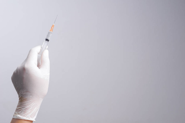Hand wearing latex glove holding syringe with a medicine - Fotó, kép