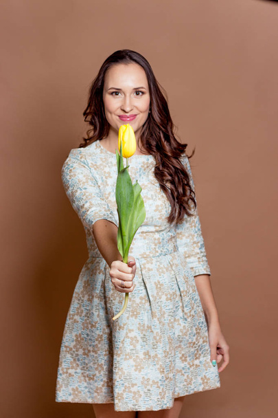 Young beautiful woman holding a bouquet of yellow tulips. Spring. - Фото, зображення