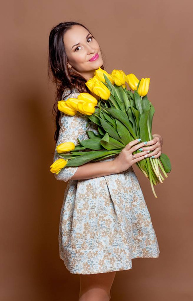 Young beautiful woman holding a bouquet of yellow tulips. Spring. - Foto, immagini