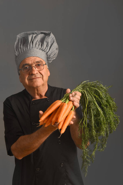 portrait of a senior chef with carrots - Photo, Image