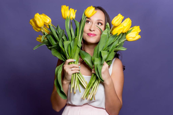 Молода красива жінка тримає букет жовтих тюльпанів. Весна
. - Фото, зображення