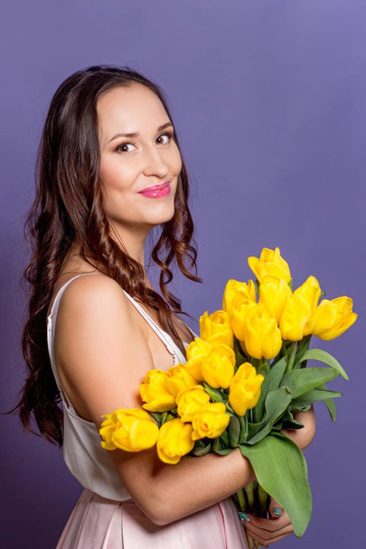 Young beautiful woman holding a bouquet of yellow tulips. Spring. - Foto, Bild