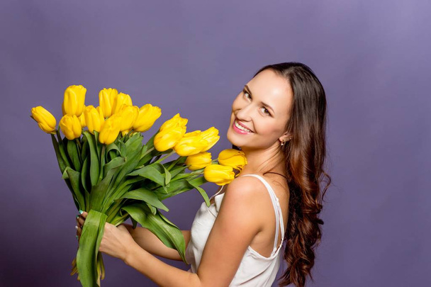 junge schöne Frau mit einem Strauß gelber Tulpen. Frühling. - Foto, Bild