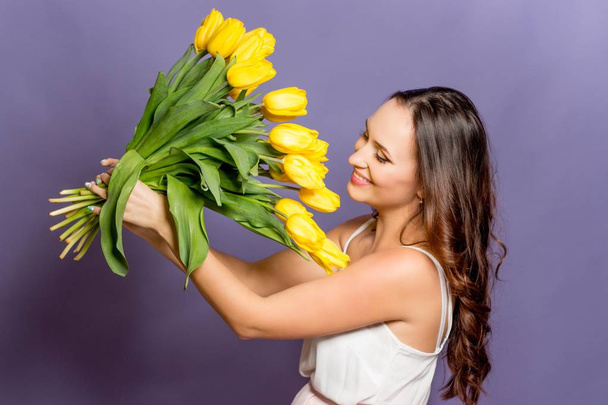 Fiatal gyönyörű nő kezében egy csokor sárga tulipánok. Tavaszi. - Fotó, kép
