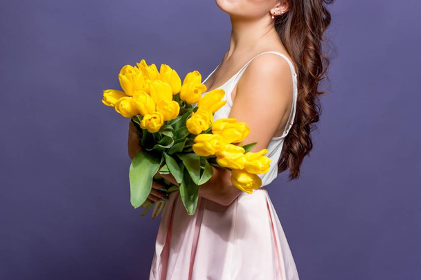Young beautiful woman holding a bouquet of yellow tulips. Spring. - Foto, immagini