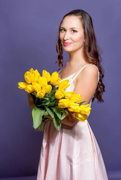 黄色のチューリップの花束を保持している若い美しい女性。春. - 写真・画像