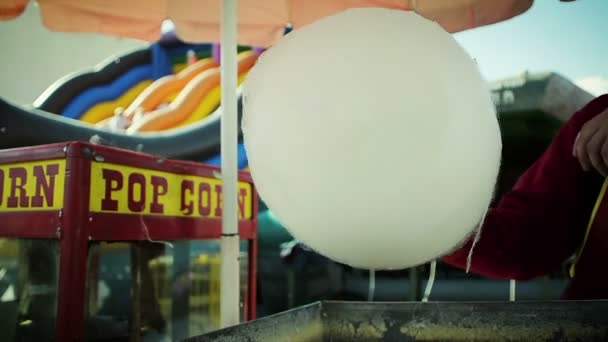 Primer plano de un hombre cocinando un hilo de azúcar en el parque de atracciones
 - Metraje, vídeo
