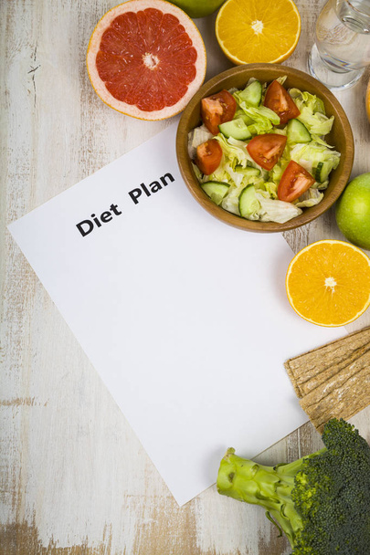 Food and sheet of paper with a diet plan on a  wooden table.  - Fotoğraf, Görsel