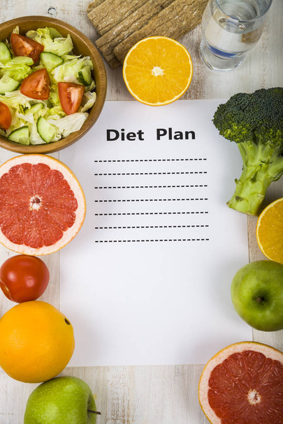 Food and sheet of paper with a diet plan on a  wooden table.  - Foto, immagini